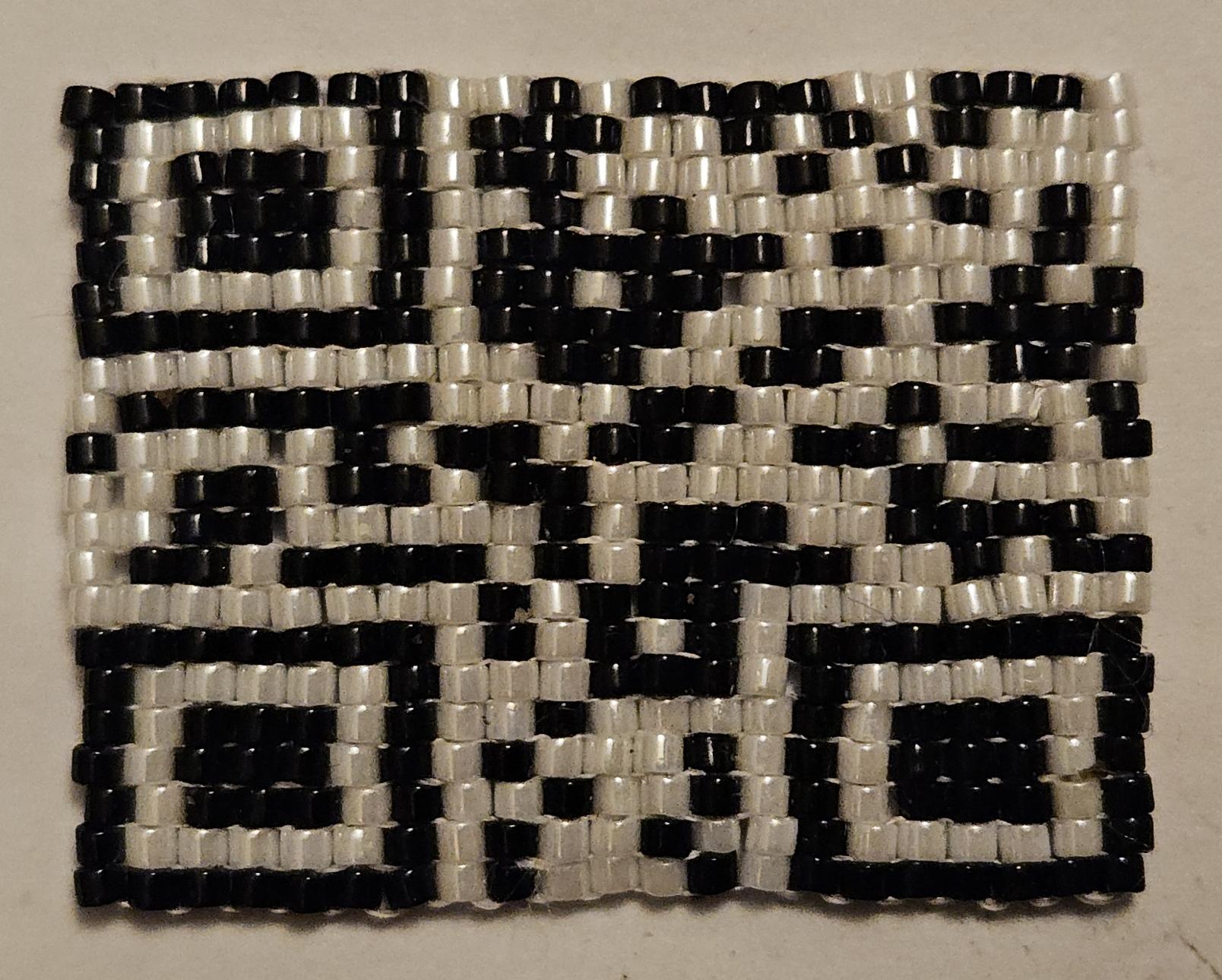 A QR code made out of woven beads.